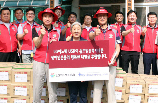 박종석(앞줄 오른쪽) LG이노텍 사장과 김동의 노조위원장(앞줄 왼쪽) 등 LG이노텍 관계자들이 23일 중증장애인 거주시설인 홀트일산복지타운을 찾아 봉사활동을 하고 조병국(앞줄 가운데) 홀트부속의원 명예원장에게 이곳 장애인들이 1년간 사용할 수 있는 분량의 샴푸, 비누 등 생활용품을 전달했다./사진제공=LG이노텍