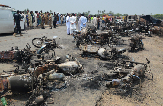 파키스탄 펀자브주 바하왈푸르 고속도로에서 유조차 폭발사고가 일어난 가운데 주민들과 경찰들이 불에 탄 오토바이 등 사고 잔해를 살펴보고 있다./바하왈푸르=EPA연합뉴스