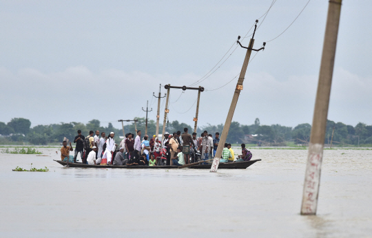 4일(현지시간) 인도 북동부 아삼주 모리가온의 발리무크 마을에서 홍수로 고립된 주민들이 강으로 변한 들판 위로 배를 타고 대피하고 있다. 6~9월 우기를 맞은 인도에서는 최근 이어진 폭우로 아삼주에서만 35만명의 이재민이 발생하는 등 큰 피해를 입었다. /모리가온=AFP연합뉴스