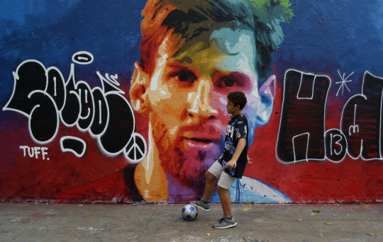 한 어린이가 리오넬 메시의 벽화로 장식돼 있는 스페인 바르셀로나의 한 골목에서 축구연습을 하고 있다. /바르셀로나=AP연합뉴스