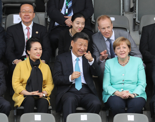 시진핑(가운데) 중국 국가주석이 5일(현지시간) 주요20개국(G20) 정상회의 참석을 위해 방문한 독일 베를린에서 부인 펑리위안(왼쪽) 여사 등과 함께 중·독 청소년 친선축구를 관람하며 미소짓고 있다. /베를린=신화연합뉴스