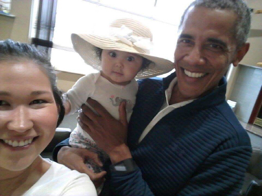 버락 오바마 전 미국 대통령이 귀국 중 알래스카 앵커리지 공항에서 6개월 된 여자 아이 지젤을 안고 밝게 웃고 있다. /AP연합뉴스