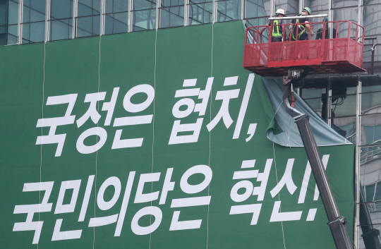 작업자들이 9일 서울 여의도 국민의당 당사 외벽에서 ‘협치’를 강조한 문구가 적힌 현수막을 철거하고 있다. /연합뉴스