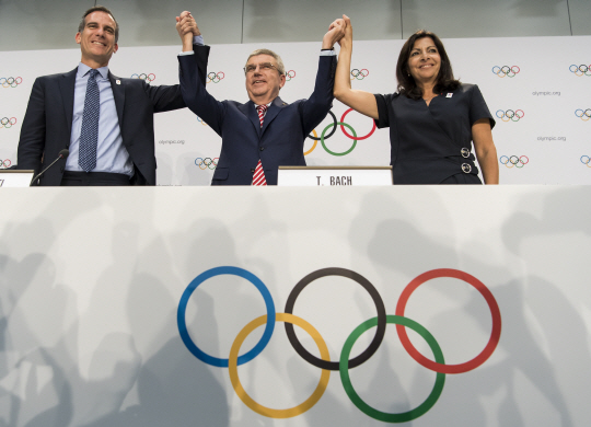 토마스 바흐(가운데) 국제올림픽위원회(IOC) 위원장이 11일(현지시간) 스위스 로잔에서 열린 IOC 총회에서 에릭 가세티(왼쪽) 미국 로스앤젤레스(LA) 시장, 안 이달고 프랑스 파리 시장과 잡은 손을 들어 올리고 있다. /로잔=EPA연합뉴스