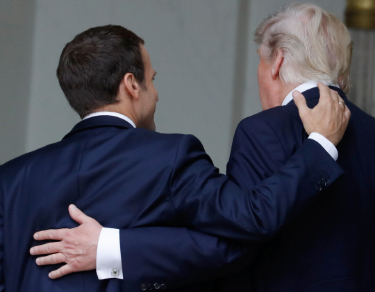 13일(현지시간) 에마뉘엘 마크롱(왼쪽) 프랑스 대통령과 도널드 트럼프 미국 대통령이 프랑스 파리에서 어깨동무를 하는 등 30세 넘는 나이차에도 불구하고 브로맨스를 과시하고 있다. /파리=AFP연합뉴스