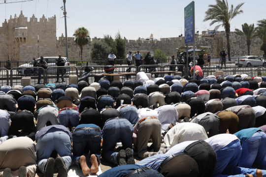 이슬람교도와 이스라엘 경찰 간 총격전이 벌어진 이스라엘 예루살렘의 템플마운트에서 14일(현지시간) 이번 사건으로 근처의 모스크(이슬람 사원)가 폐쇄돼 예배에 맞춰 모이지 못한 무슬림들이 사원 문 앞에 모여 기도를 올리고 있다.   /예루살렘=AFP연합뉴스