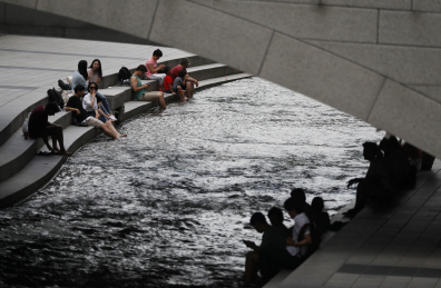 14일 오후 서울 종로구 청계천을 찾은 시민과 관광객들이 물에 발을 담그며 더위를 식히고 있다. /연합뉴스