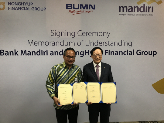 김용환(오른쪽) NH농협금융 회장이 17일 인도네시아 만디리은행 본점에서 카르티카 위르조아트모조 만디리은행장과 상호 협력 및 발전을 위한 업무협약(MOU)을 체결하고 있다./사진제공=NH농협금융