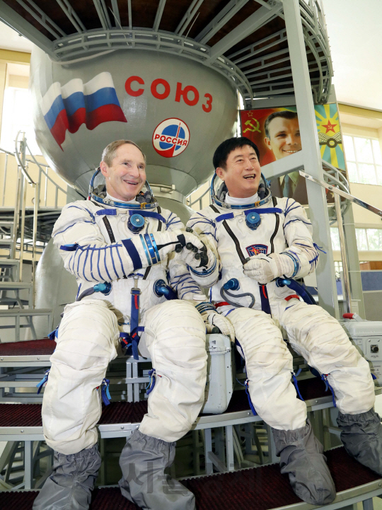 정찬민(오른쪽) 용인시장이 18일 스타시티의 ‘유리 가가린 우주비행사 훈련센터’에서 토카레프 발레리 이바노비치 시장과 우주복을 입고 앉아 악수하고 있다./사진제공=용인시청