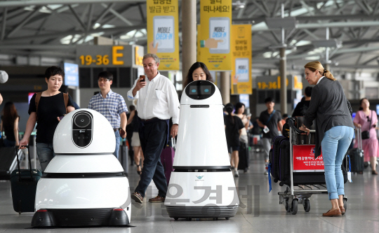 LG전자가 상업용 로봇 시범 서비스를 시작한 첫날인 21일 인천국제공항을 찾은 여행객들이 신기한 표정으로 안내로봇과 청소로봇을 구경하고 있다. 이번 서비스는 인천국제공항에서 실시하는 스마트공항 서비스의 일환으로 LG전자가 안내로봇과 청소로봇을 각각 5대씩 배치했다. 안내로봇은 한국어·영어·중국어·일본어 등 4개 국어를 인식하며 공항 이용객에게 항공편 정보 등을 제공한다.    ★관련기사 11면 /이호재기자