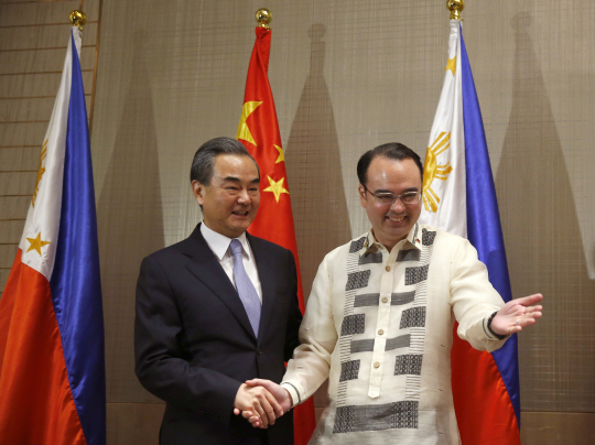 왕이(왼쪽) 중국 외교부장이 25일 알란 카예타노 필리핀 외무장관의 안내를 받고 있다. /마닐라=AP연합뉴스