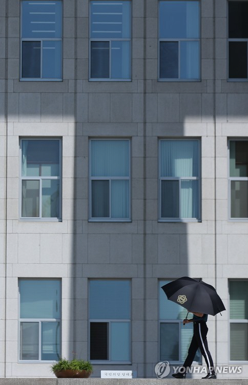 여의도 국회 의사당에서 경찰 관계자가 햇빛가리개용으로 우산을 쓰고 근무를 서고 있다. /연합뉴스