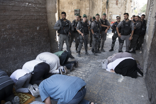 예루살렘 구시가지에 있는 ‘사자의 문’ 앞에서 25일(현지시간) 이슬람 신도들이 기도하는 모습을 이스라엘 군인들이 지켜보고 있다. /예루살렘=EPA연합뉴스