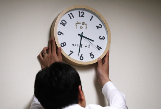 청와대의 한 직원이 27일 오후 벽에 걸린 시계의 각도를 바로잡고 있다. /연합뉴스