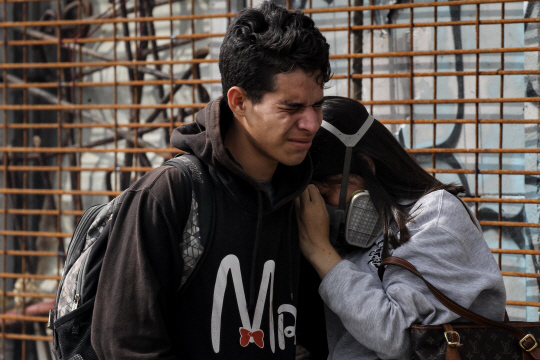 베네수엘라 반정부 시위에 참여한 두 명의 시민이 27일(현지시간) 수도 카라카스에서 치안당국이 최루탄을 발사하자 얼굴을 찡그리고 있다. /카라카스=EPA연합뉴스