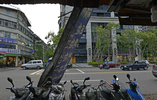 30일 타이완 시내 한 도로변에 세워진 오토바이 뒤로 태풍의 영향을 받아 인근 빌딩에서 떨어진 간판이 놓여있다./타이완=AFP연합뉴스
