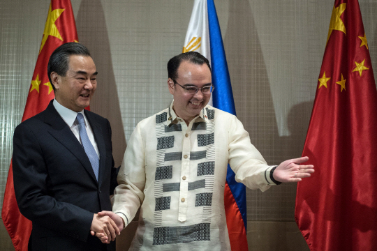 왕이(왼쪽) 중국 외교부장이 지난 25일 필리핀 마닐라에서 알란 카에타노 필리핀 외교부 장관과 악수하고 있다. /마닐라=AFP연합뉴스