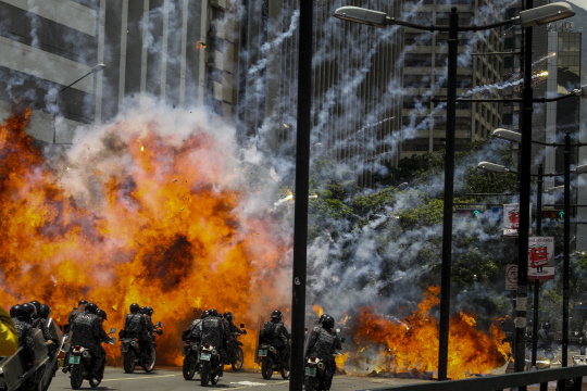 30일(현지시간) 베네수엘라 수도 카라카스 알타미라광장 인근에서 반정부시위대가 터뜨린 사제폭탄이 오토바이를 탄 경찰들 앞에서 폭발하고 있다.  /카라카스=EPA연합뉴스