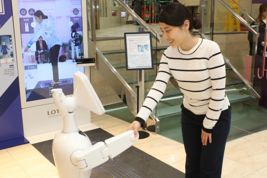 한 고객이 서울 명동 롯데백화점 본점에서 쇼핑도우미 로봇 ‘엘봇’과 악수를 나누고 있다. /사진제공=롯데백화점