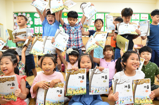 여름방학을 끝내고 16일 등교한 서울 노원구 신계초등학교 학생들이 2학기 새 교과서를 들고 환하게 웃고 있다. /송은석기자
