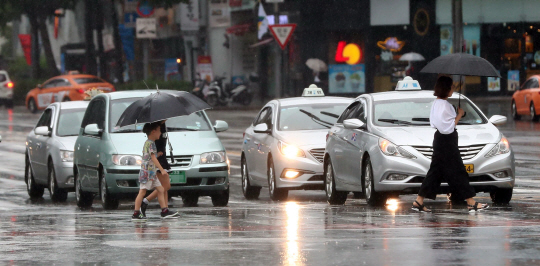 전국이 흐리고 비가 내리는 20일 오전 서울 종로구 광화문 세종대로 사거리에서 우산을 쓴 시민들이 발걸음을 옮기고 있다. /연합뉴스