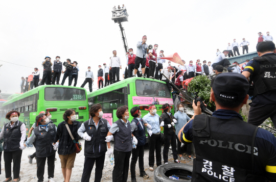 23일 서울 거여동의 버스회사 송파상운 차고지에서 이 회사 직원들이 인간띠를 만들고 버스 위에 올라가 재개발 강제 철거 집행에 반발하고 있다.  　 /권욱기자