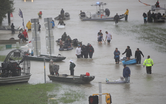 28일(현지시간) 미국 텍사스주 휴스턴시에서 집에서 나온 사람들이 홍수로 물에 잠긴 도로로 빠져 나오고 있다. /휴스턴=AFP연합뉴스
