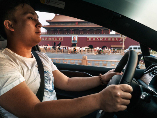 공정 거래 : 마이크 팬이 자신의 모델 X를 타고 베이징 천안문 광장을 지나고 있다. 테슬라는 중국의 고급 자동차 중개대리점을 통해 판매되지 않는다. 따라서 구매자들은 추가 비용을 부담하지 않아도 된다.