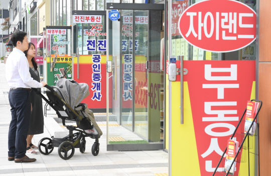 유모차에 아기를 태운 부부가 서울 서대문구의 한 부동산중개소 앞에서 전세 매물을 살펴보고 있다. 치솟는 생활비와 육아에 대한 부담으로 자녀 갖기를 포기하거나 아이 하나만 낳는 가정이 늘고 있다. /송은석기자