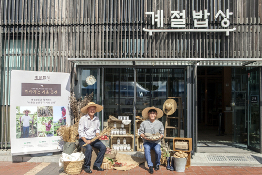 계절밥상 올림픽공원점에서 열린 ‘친환경 농산물 직거래 장터’에서 한창본(왼쪽) 농부와 김동우 농부가 직접 재배한 작물을 들어보이고 있다. /사진제공=CJ푸드빌