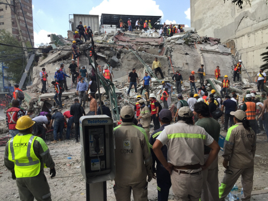 19일(현지시간) 멕시코 수도 멕시코시티에서 구조대가 붕괴된 건물에서 생존자를 찾고 있다.  /멕시코시티=AP연합뉴스