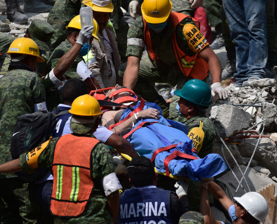 지난 19일(현지시간) 멕시코 중부 지역을 덮친 규모 7.1의 강진으로 무너진 건물더미에서 20일 한 남성이 구조되고 있다. 이번 지진으로 사망한 이는 21일 0시 현재 230명으로 최종 확인됐다.   　 /멕시코시티=AFP연합뉴스