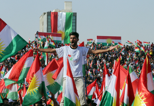 22일(현지시간) 쿠르드족 독립 찬성 집회가 열린 쿠르드자치정부(KRG)의 수도 이라크 에르빌에서 한 청년이 쿠르드족을 상징하는 깃발에 둘러싸여 분리독립을 요구하는 함성을 지르고 있다. /에르빌=EPA연합뉴스