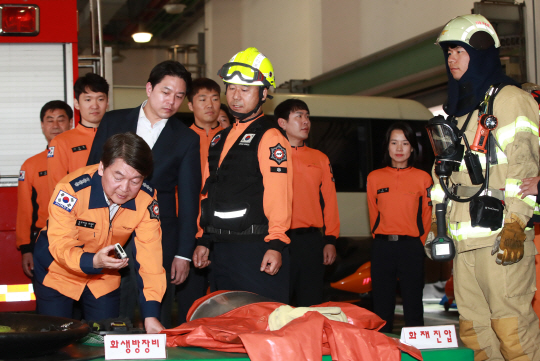 안철수(왼쪽) 국민의당 대표가 1일 서울 용산소방서를 찾아 소방대원들의 출동 장비에 대한 설명을 듣고 있다. /연합뉴스