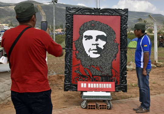 지난 9일(현지시간) 볼리비아 중부 도시 바예그란데에서 아르헨티나 출신 혁명가 에르네스토 체 게바라 사망 50주년 기념식이 열리고 있는 와중 한 남성이 체 게바라 그림 옆에서 사진을 찍고 있다./AFP