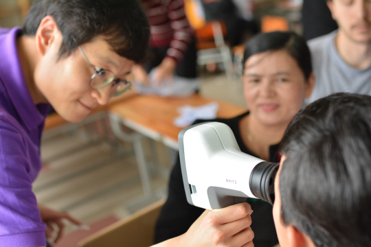 오비츠 소속 직원이 휴대용 시력측정기기로 개발도상국 아이들의 시력을 측정해주고 있다./사진제공=오비츠