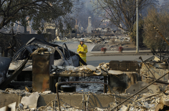 12일(현지시간) 미국 캘리포니아주 북부 소나마 카운티 샌타로자에서 한 소방관이 산불로 폐허로 변한 주택가를 조사하고 있다. /소노마=AP연합뉴스