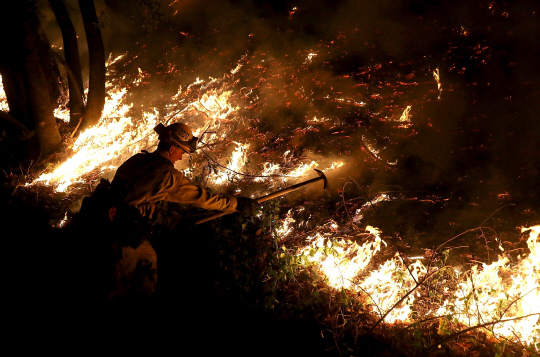 12일(현지시간) 미국 캘리포니아 칼리스토가 인근에서 한 소방관이 여전히 맹위를 떨치는 산불과 싸우고 있다./칼리토스=AFP연합뉴스