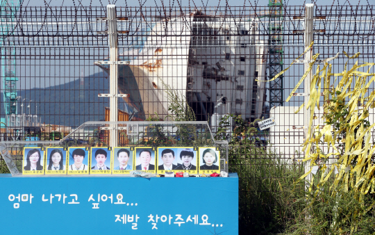 목포신항에 거치된 세월호 앞 철조망 너머에 미수습자의 사진이 놓여 있다.  /연합뉴스