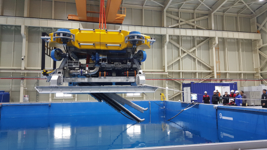 수중건설로봇사업단 관계자들이 중작업용 수중건설로봇(URI-T) 시제품을 테스트하기 위해 호이스트에 매달아 시험용 수조에 넣고 있다. /제공=수중건설로봇사업단.