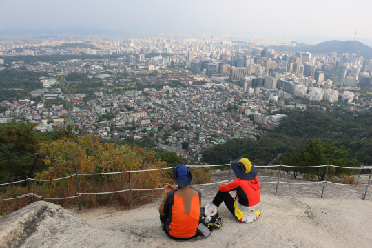 인왕산 등반객이 산 정상에서 서울 도심을 내려다보고 있다. 바로 아래가 서촌이고 중간쯤이 경복궁이다. 오른쪽에 남산도 보인다.