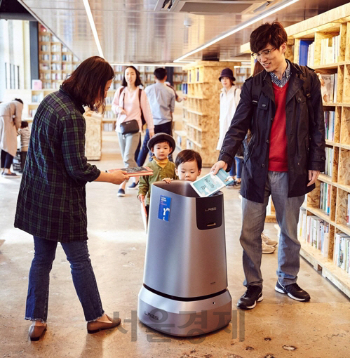 부산에 있는 예스24의 중고서점에서 방문객들이 자율주행 로봇 ‘어라운드’에 다 읽은 책을 집어 넣고 있다. /사진제공=예스24