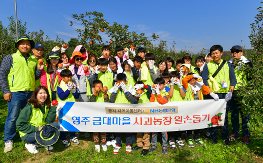 지역아동센터 ‘둥지’ 학생들과 경북 영주 금대마을 주민들, 농협은행 홍보국 직원들이 지난 26일 사과농장에서 수확을 진행한 후 기념촬영을 하고 있다./사진제공=NH농협은행