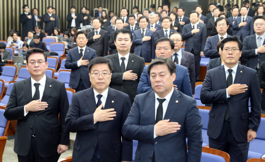 정우택(왼쪽) 자유한국당 원내대표와 의원들이 30일 오전 국회에서 열린 의원총회에서 국기에 경례를 하고 있다. 이날 한국당 의원들은 검은양복을 입고 의총에 참석했다./연합뉴스