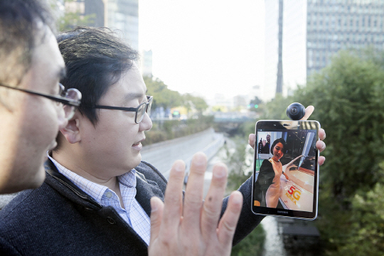 SK텔레콤 연구원들이 청계천에서 삼성전자 태블릿 단말기를 5G 시험망에 연동해 5G 360 VR 영상 통화 서비스를 시연하고 있다./사진제공=SK텔레콤