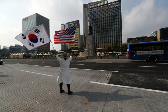 트럼프 미국 대통령 방한을 나흘 앞둔 3일 한 시민이 서울 종로구 광화문 거리에서 태극기와 성조기를 함께 흔들고 있다. /연합뉴스