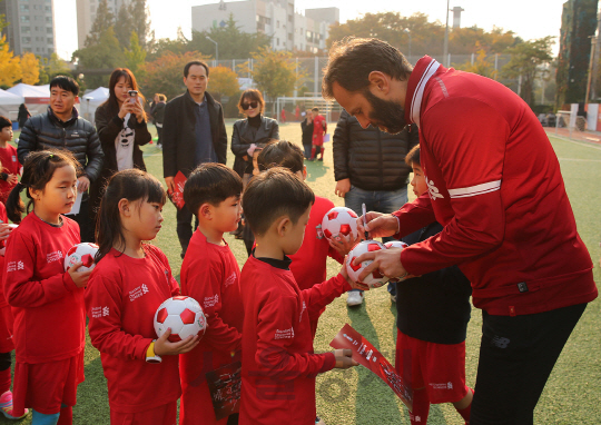 패트릭 베르게르(오른쪽) 리버풀FC 레전드 선수가 4일 서울 서초구 ‘덜위지칼리지 서울영국학교’에서 SC제일은행 주최로 열린 ‘리버풀 축구교실’ 참가 어린이들에게 사인을 해주고 있다./사진제공=SC제일은행