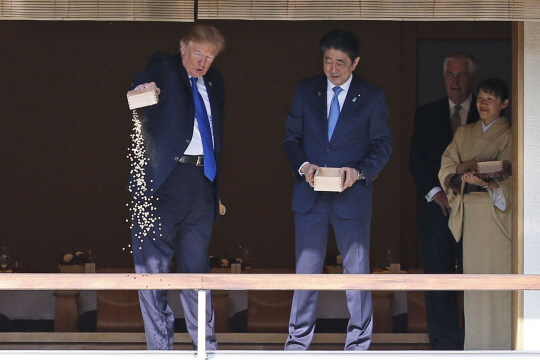 도널드 트럼프(왼쪽 첫번째) 미국 대통령이 6일 도쿄 아카사카 궁 연못에 들러 상자 속 먹이를 쏟아붓고 있다. /도쿄=AP연합뉴스