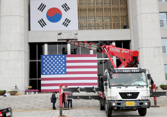 도널드 트럼프 미국 대통령의 국회연설을 하루 앞둔 7일 오전 서울 여의도 국회의사당 앞에서 작업자들이 국회 벽면에 걸 한국과 미국 양국 국기를 국회 본관에 붙이고 있다. /연합뉴스