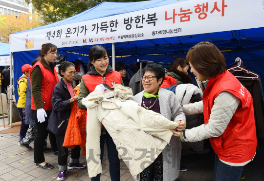 KT그룹 임직원 봉사단원들이 7일 서울 용산구 동자동 새꿈어린이공원에서 열린 '온기가 가득한 방한복 나눔' 행사에서 쪽방촌 주민들에게 방한복을 나눠주고 있다./권욱기자